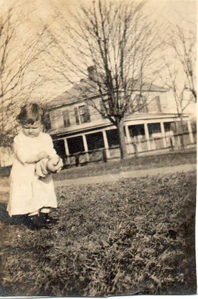 judith-in-front-yard-of-grandparents-with-her-home-in-background-img336